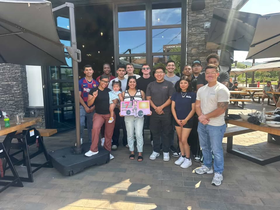 Customer group on a patio holding a pink barbell character plaque