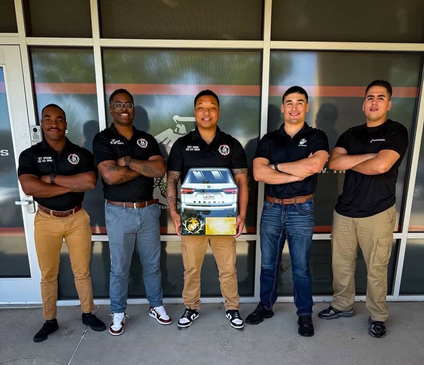 Team holding a personalized vehicle-shaped plaque