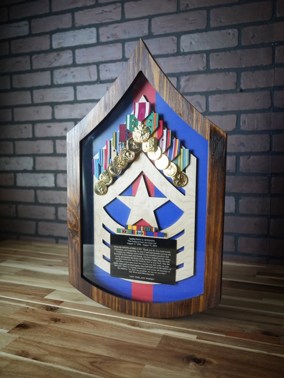 Curved wooden Marine rank shadow box with mounted medals, ribbons, and a message plate