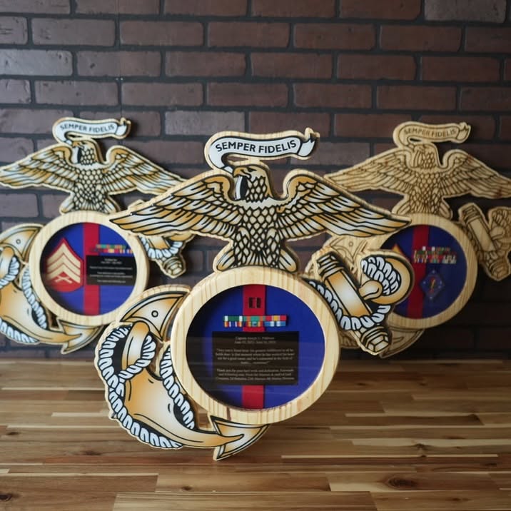 Three Eagle, Globe, and Anchor shadow boxes on a tabletop against a brick wall