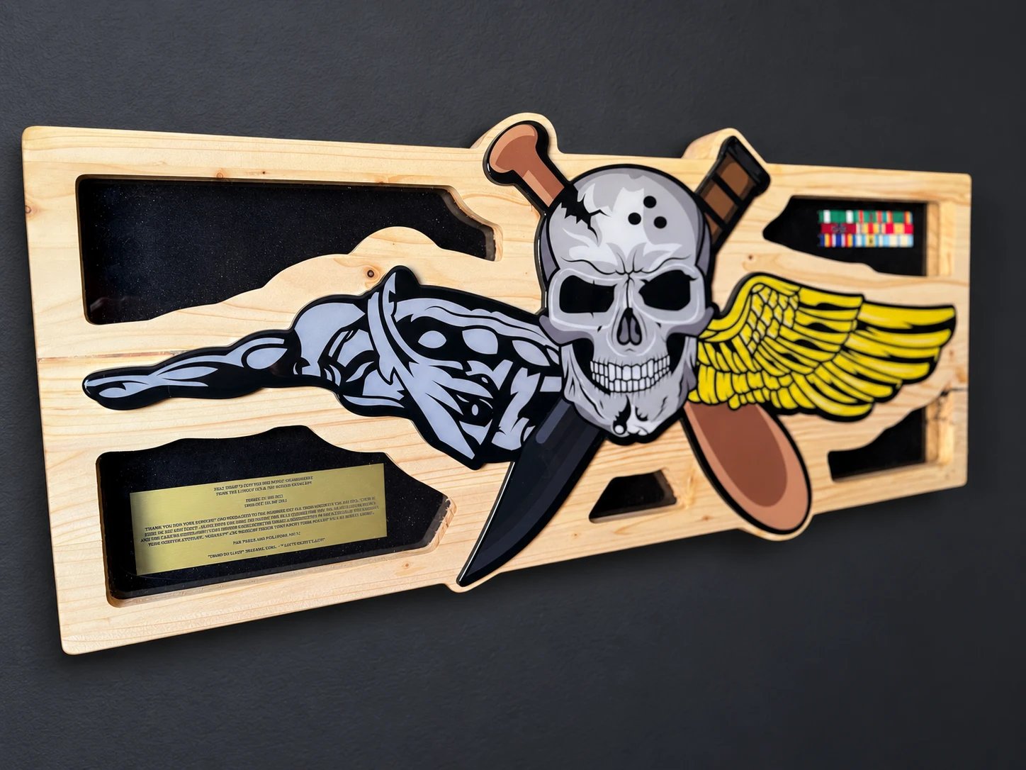 Wide custom shadow box with a skull, paddle, dagger and wings, plus a plaque and ribbons